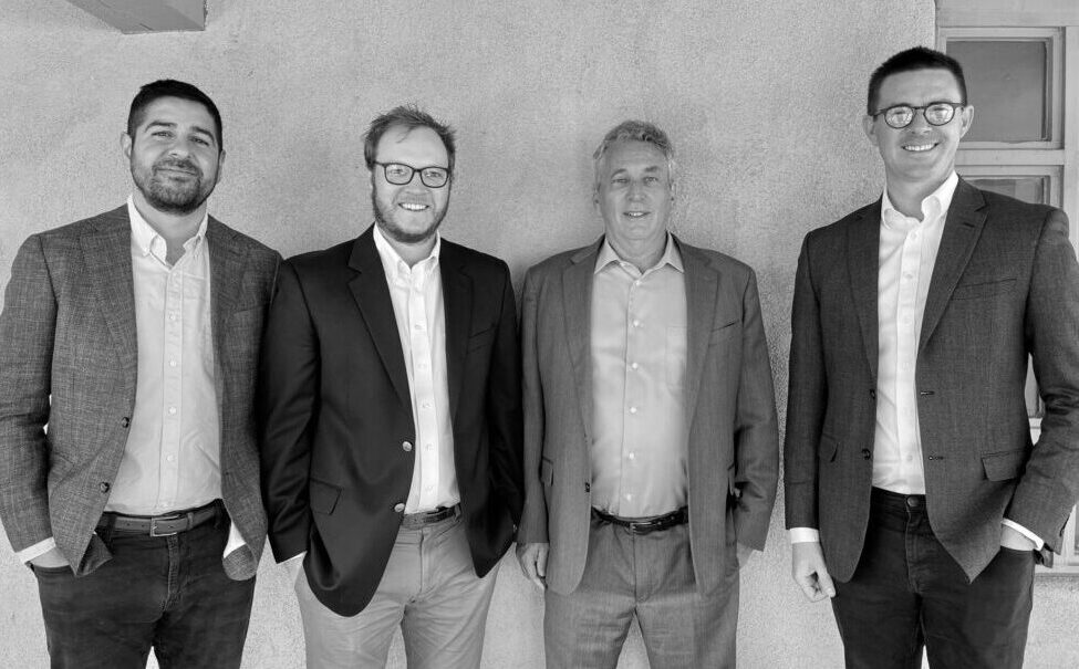 Black-and-white photo of four partners standing outside their office